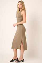 woman wearing a khaki sleeveless midi dress with side slits and black heeled mules