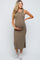 woman wearing a brown sleeveless maternity dress, holding her baby bump, styled with white sneakers
