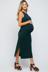 woman wearing a dark green sleeveless maternity dress with side slits and a visible baby bump