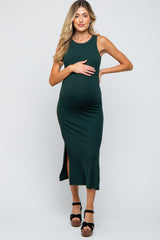 woman wearing a dark green ribbed maternity dress with a side slit and holding her baby bump