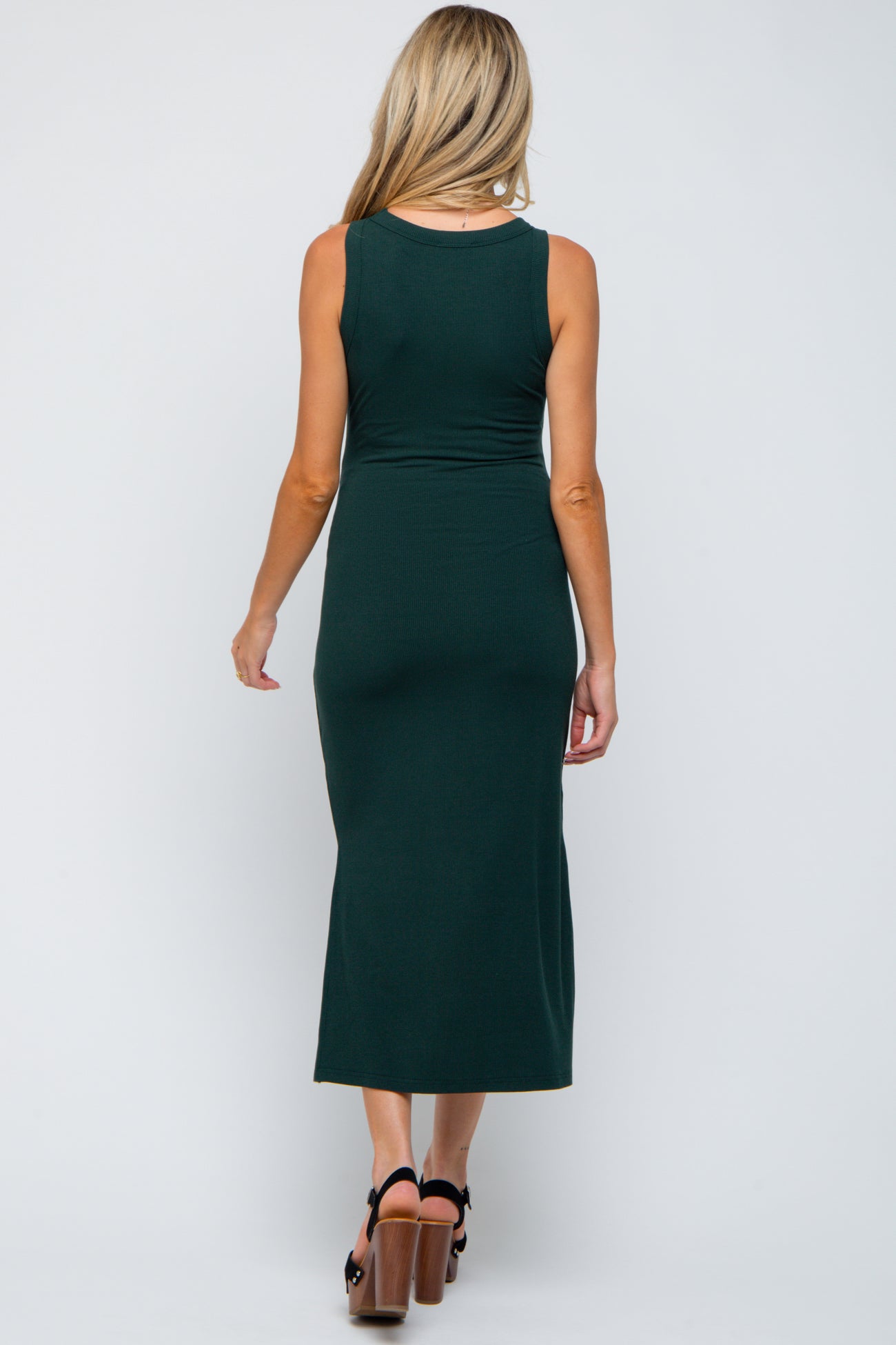 woman wearing a dark green sleeveless maternity dress, shown from the back