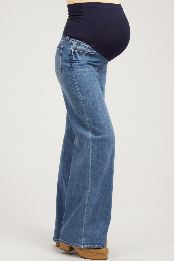 woman wearing blue maternity flared jeans with a dark blue belly panel and visible baby bump