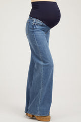 woman wearing blue maternity flared jeans with a dark blue belly panel and visible baby bump
