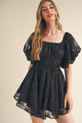 woman wearing a black lace puff sleeve mini dress with a square neckline and a fitted waist