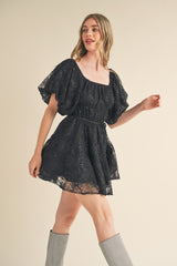 woman wearing a black lace short dress with puff sleeves and a fitted waist, paired with gray knee-high boots