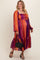 woman wearing a colorful striped maternity plus maxi dress with long sleeves and a flowing skirt, holding a black handbag