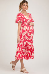 woman wearing a pink floral maternity dress with ruffled hem and holding her baby bump
