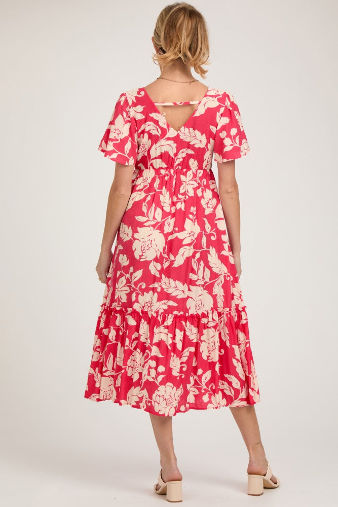 woman wearing a pink floral maternity dress with tiered ruffles and a keyhole back detail