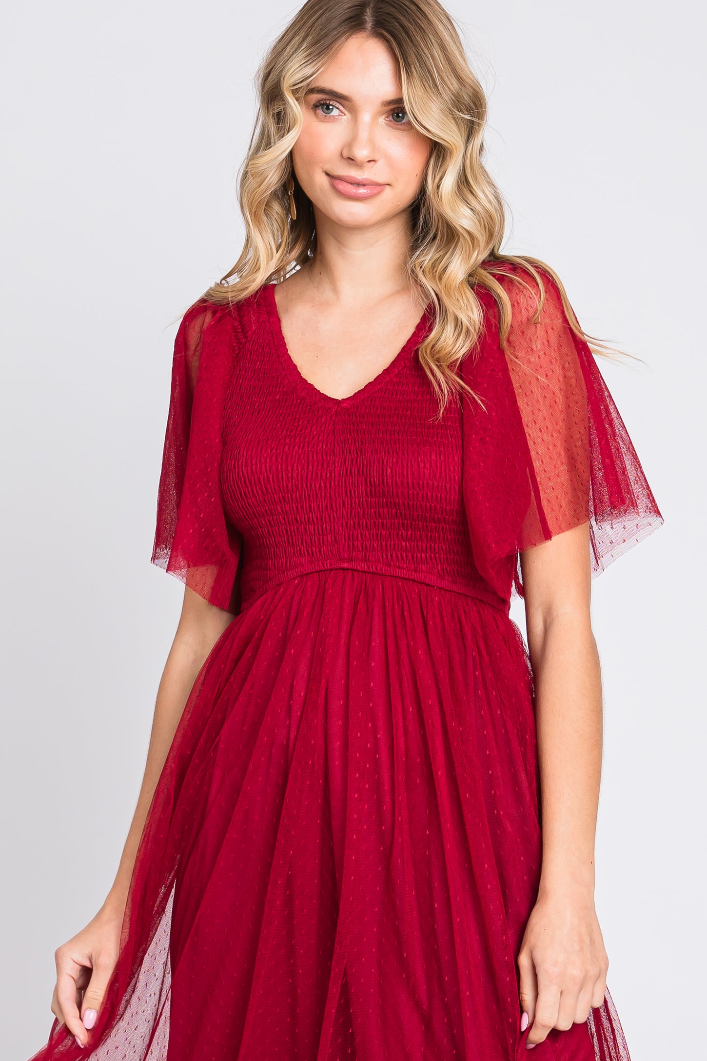 woman wearing a burgundy a-line dress with smocked bodice and sheer flutter sleeves