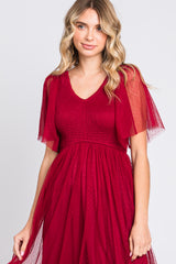woman wearing a burgundy a-line dress with smocked bodice and sheer flutter sleeves