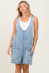 woman wearing a light wash denim romper with large front pockets and a scoop neckline