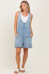 woman wearing a light blue denim overall romper with front pockets and a white tank top underneath