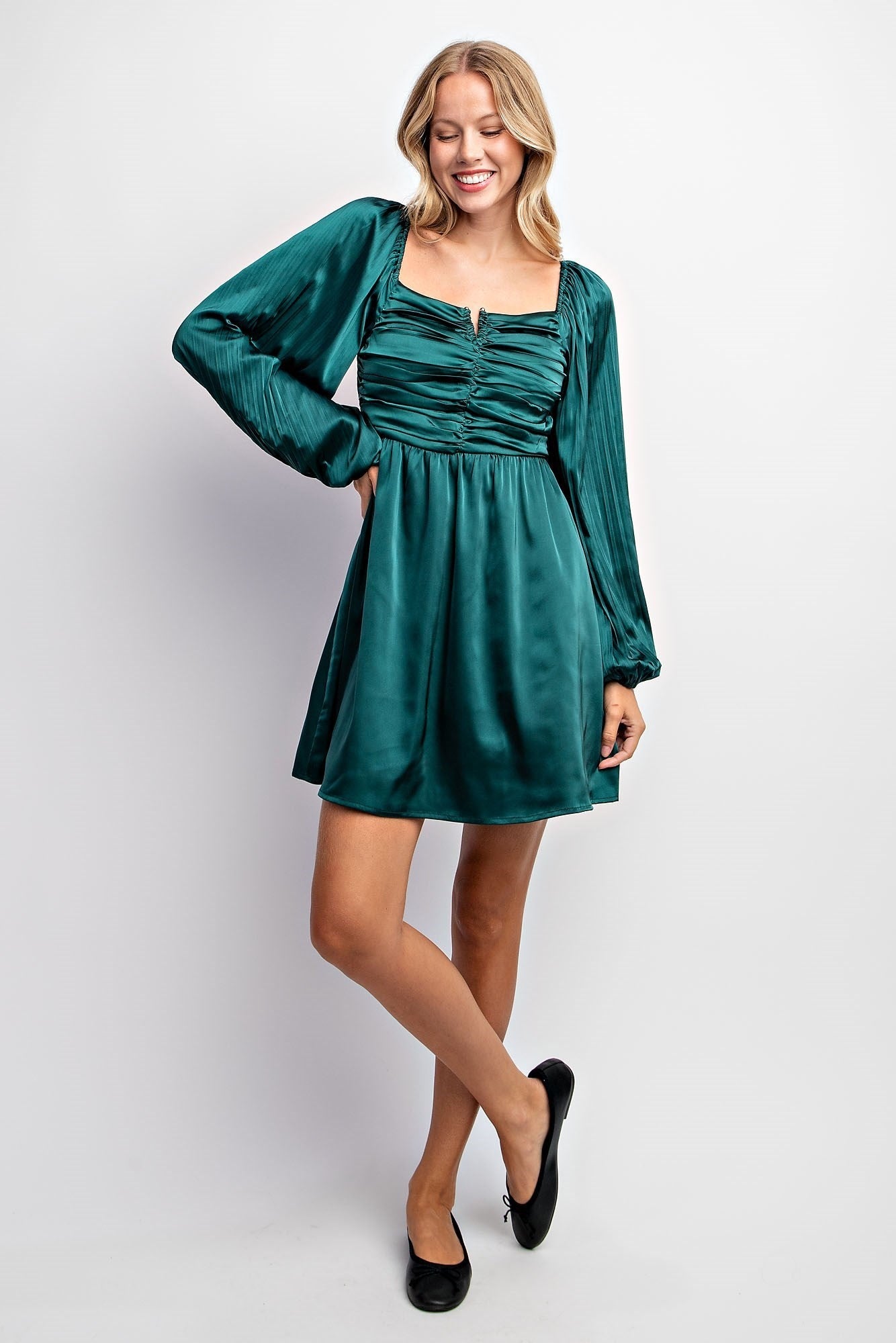 woman wearing a dark teal long sleeve mini dress with gathered front and a square neckline