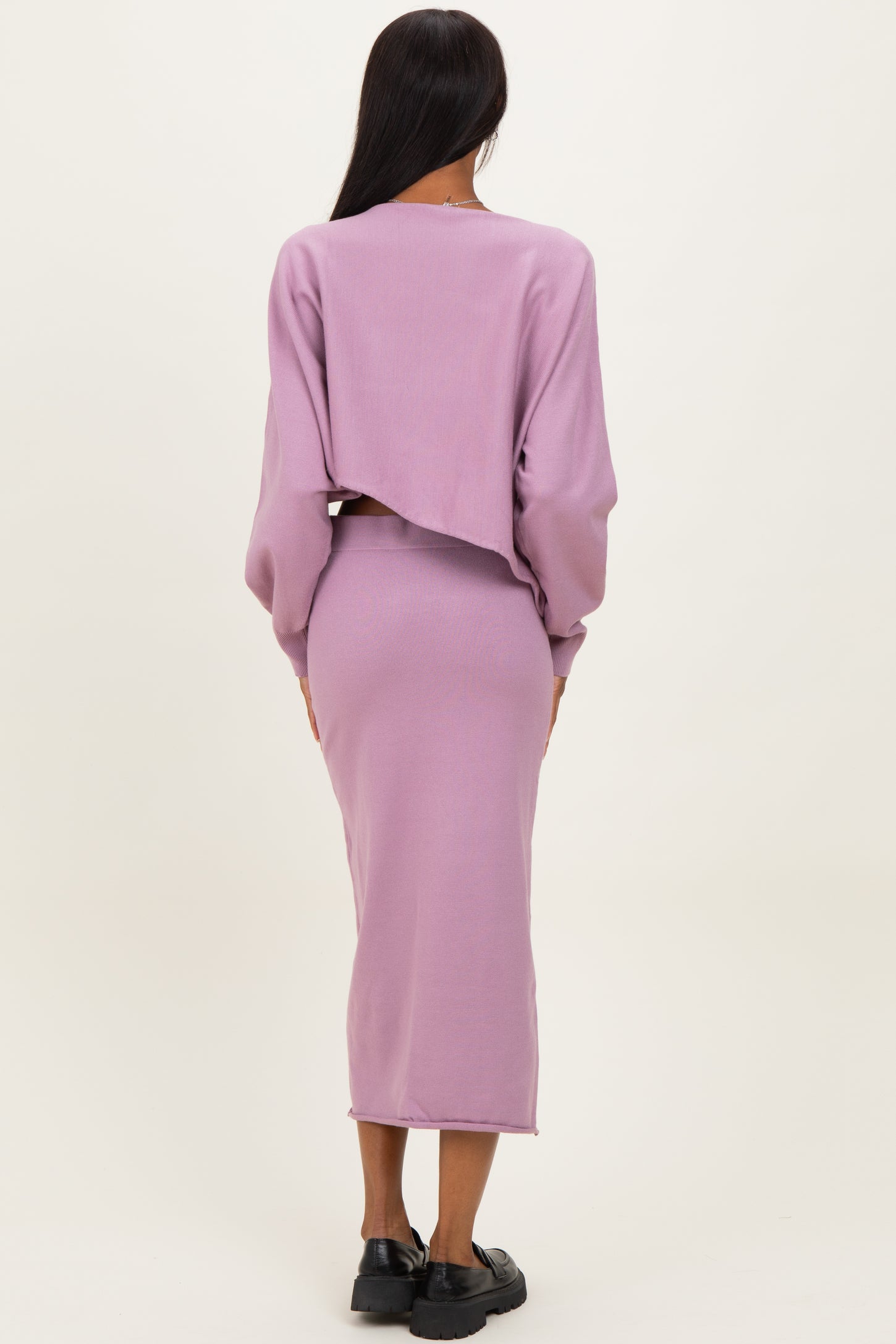 woman wearing a lilac cropped sweater and a matching midi skirt, viewed from the back