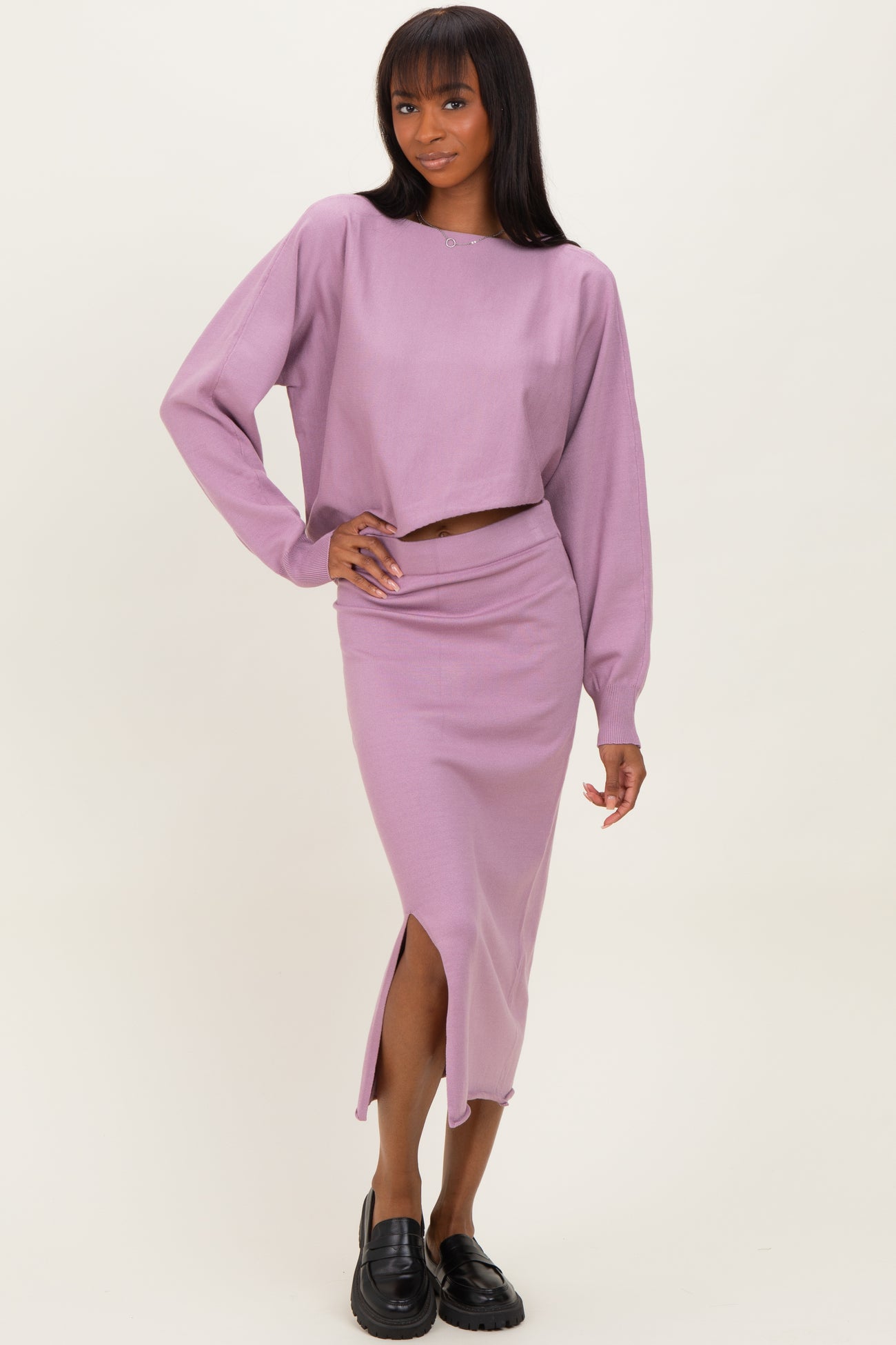 woman wearing a lavender two-piece set consisting of a cropped long sleeve top and a matching midi skirt with a slit