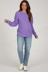 woman wearing a purple chunky knit maternity sweater and light blue distressed jeans with a relaxed fit