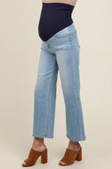 woman wearing light blue maternity jeans with a stretchy dark blue waistband and heeled sandals, showing a baby bump