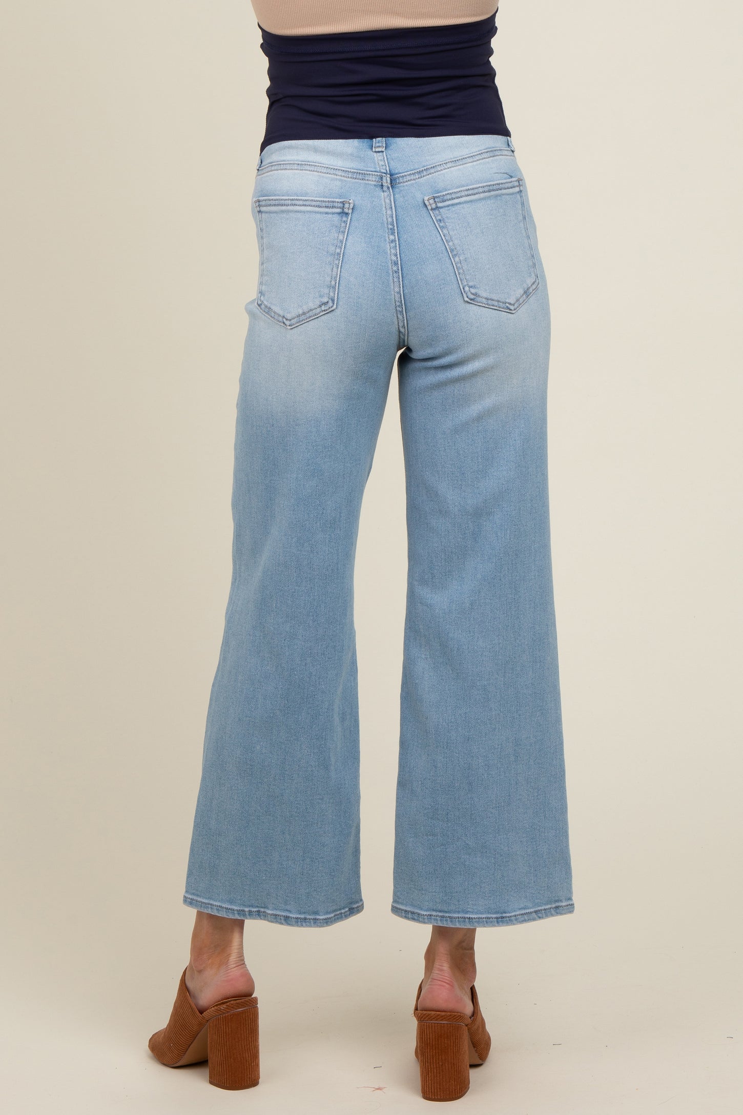 woman wearing light blue wide-leg maternity jeans, viewed from the back, showing pockets and relaxed fit