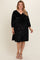 woman wearing a black velvet maternity plus dress with v-neckline and 3/4 sleeves, visible baby bump