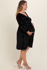 woman wearing a black floral maternity dress, holding her baby bump while standing sideways