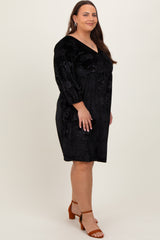 woman wearing a black floral velvet plus size dress with three-quarter sleeves and a v-neckline