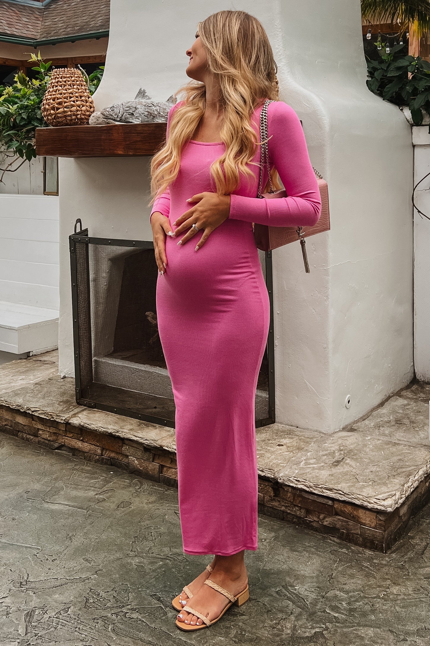 woman wearing a pink long sleeve maternity dress and holding her baby bump