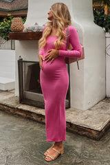 woman wearing a pink long sleeve maternity dress and holding her baby bump