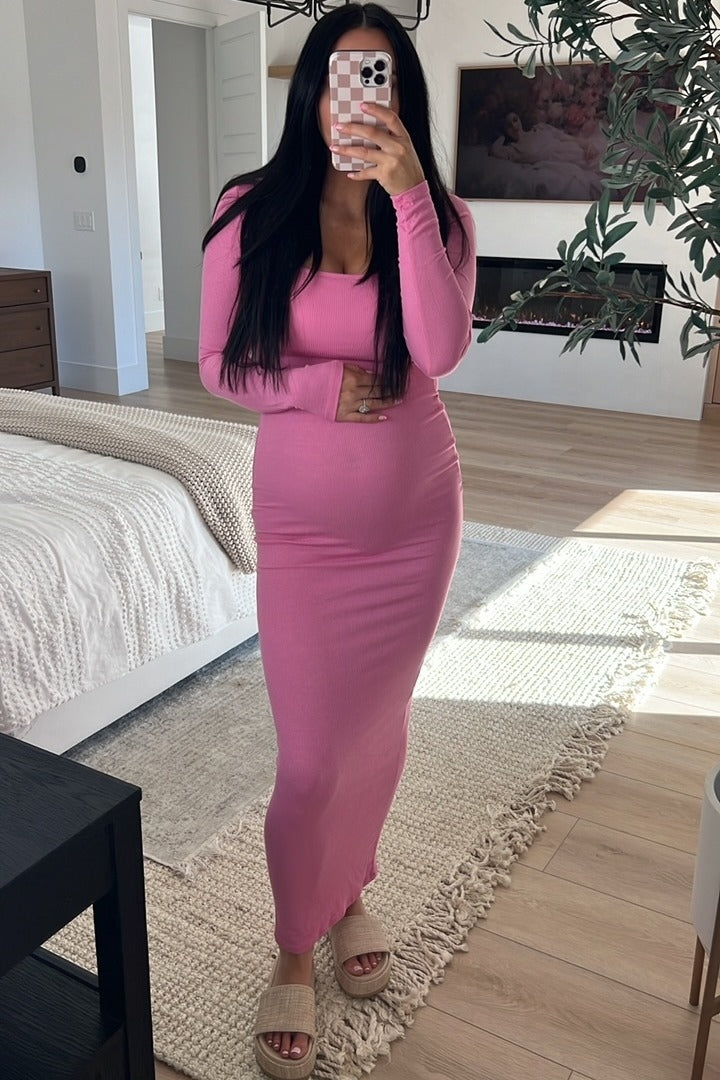 woman wearing a pink long sleeve maternity dress and holding her baby bump