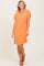 woman wearing an orange striped short sleeve casual dress with a front pocket and tan sandals