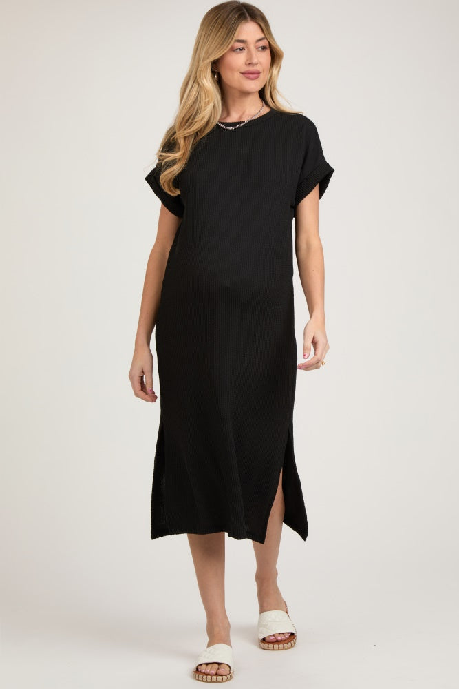 woman wearing a black maternity midi dress with short sleeves and side slits, showing her baby bump