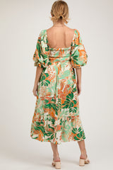 woman wearing a green floral maternity dress with puff sleeves and smocking detail, showing off a baby bump from the back