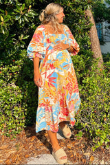 woman wearing a colorful floral maternity maxi dress and holding her baby bump while standing outdoors