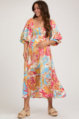 woman wearing a colorful floral maternity maxi dress with puff sleeves and a fitted bodice, holding her baby bump