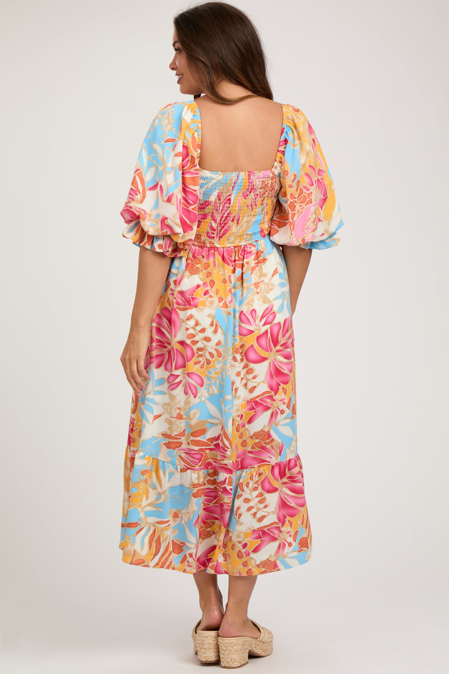 woman wearing a colorful floral maternity maxi dress with short puff sleeves and a smocked bodice