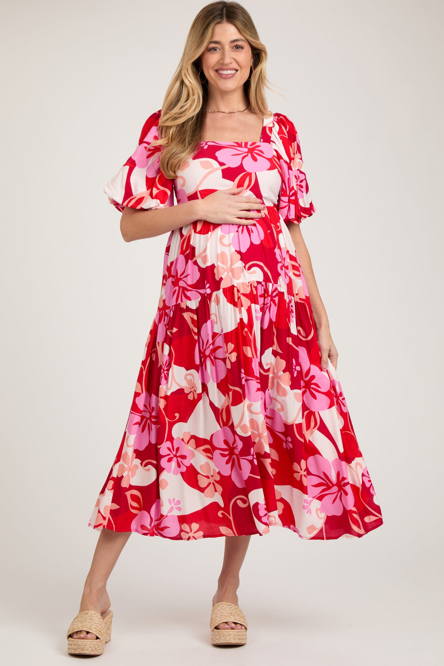 woman wearing a red floral print maternity dress with short puff sleeves and a baby bump visible