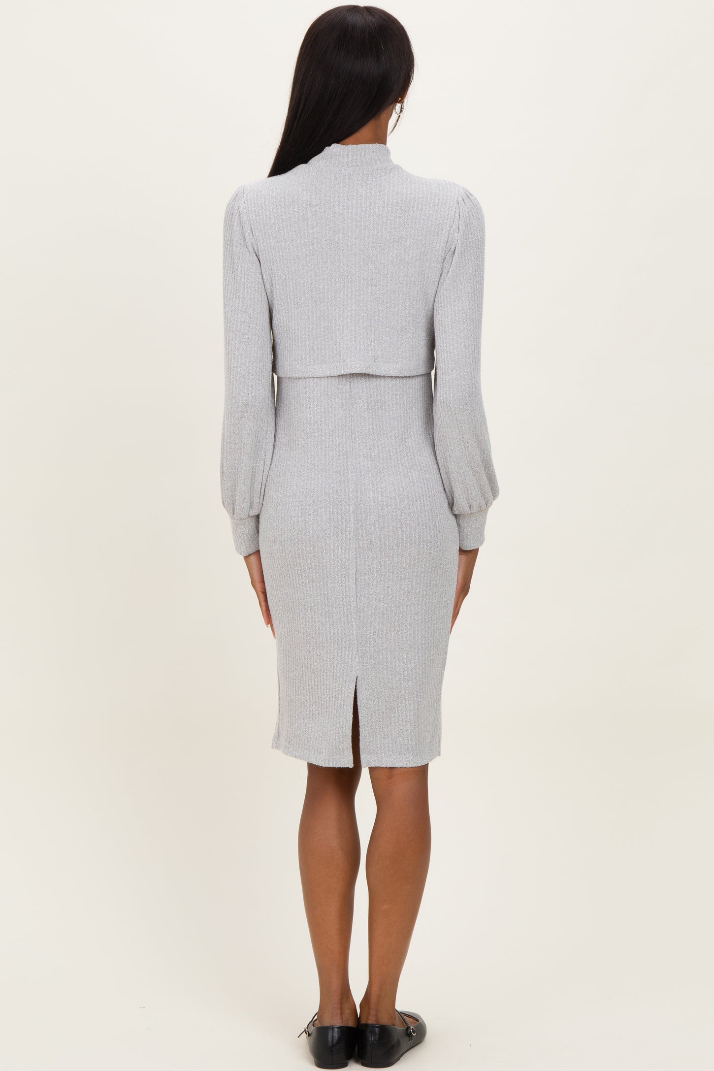 woman wearing a light gray ribbed midi dress with long puff sleeves and a fitted silhouette, viewed from the back