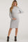 woman wearing a light gray ribbed maternity dress with long sleeves and a fitted silhouette, showing her baby bump
