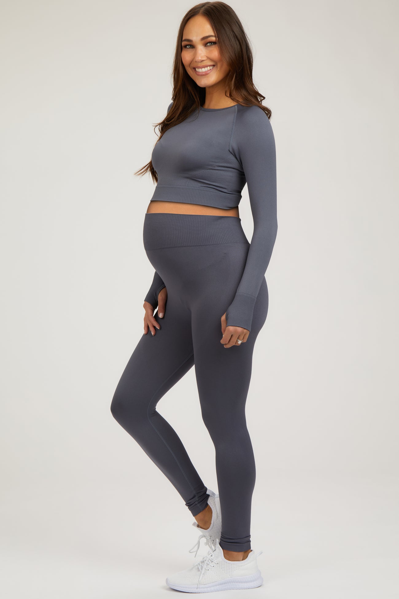woman wearing a gray long sleeve maternity crop top and matching leggings, showing her baby bump