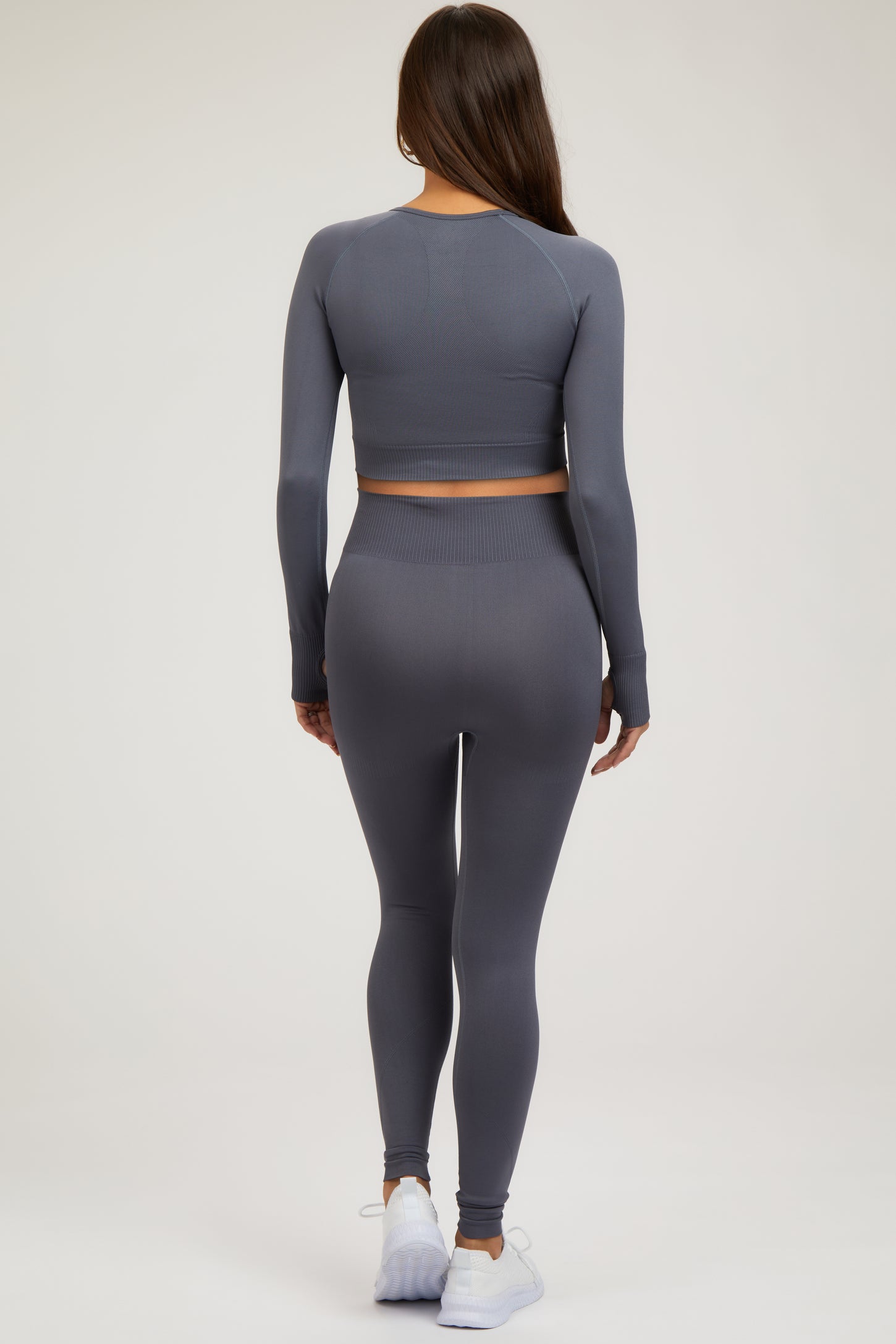 woman wearing a gray long sleeve crop top and matching leggings, styled for maternity wear