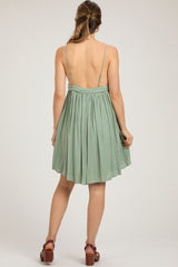 woman wearing a backless light green maternity dress with adjustable straps and a flowy skirt