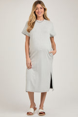 woman wearing a light gray ribbed maternity dress with side pockets and short sleeves, showcasing her baby bump