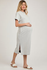 woman wearing a light gray maternity ribbed dress with side slits and holding her baby bump