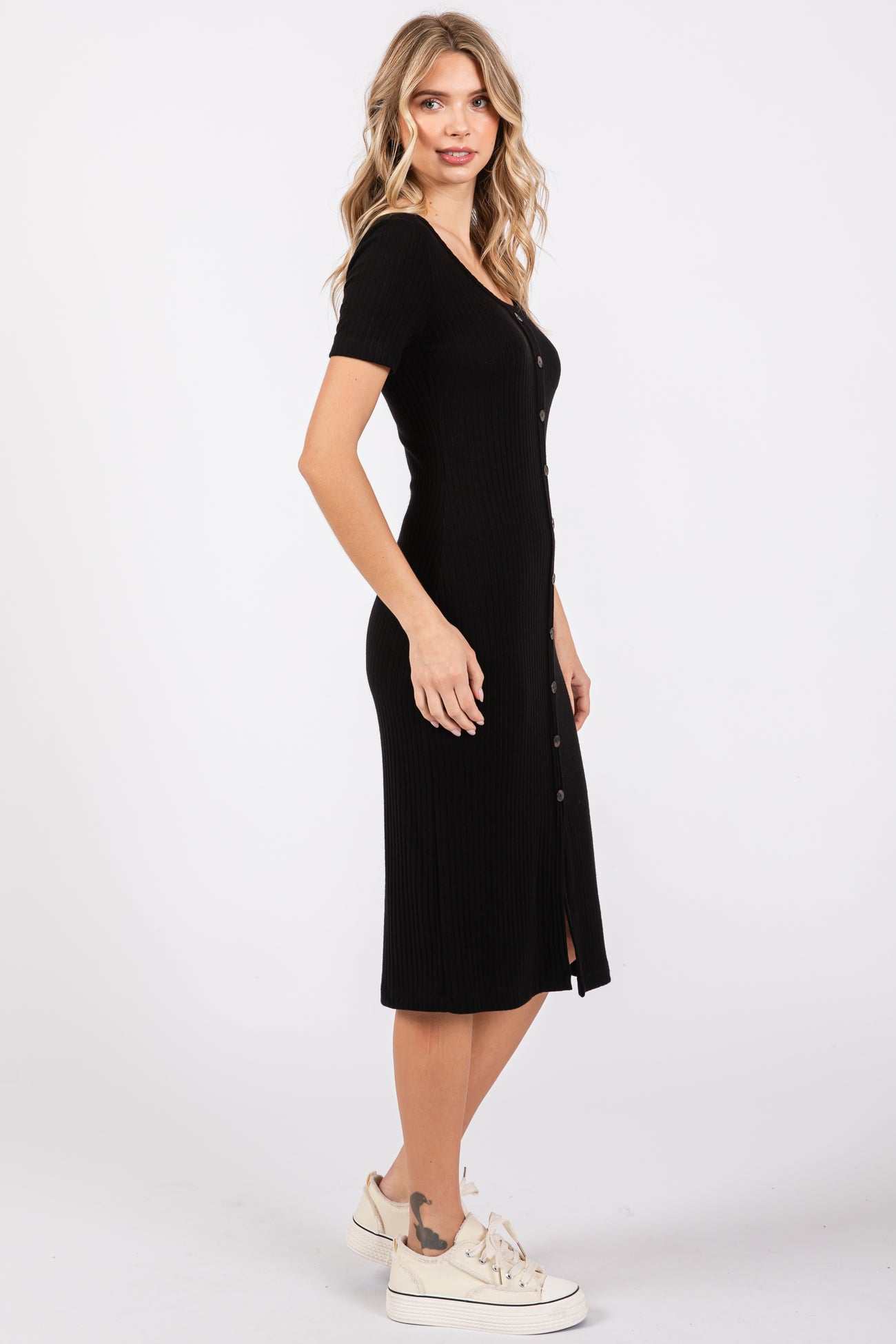 woman wearing a black ribbed midi dress with short sleeves and button details, standing sideways
