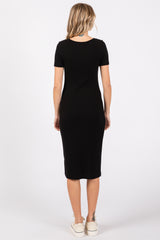 woman wearing a black ribbed midi dress with short sleeves and a fitted silhouette, standing with back to the camera