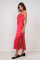 woman wearing a hot pink strapless satin dress with a side slit and tied detail at the bust