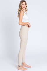 woman wearing a white crop top and beige high-waisted leggings with side pockets