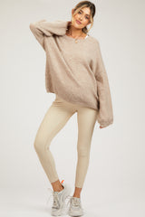 woman wearing a taupe oversized maternity sweater and beige ribbed maternity leggings