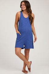 woman wearing a blue tank style maternity romper with side pockets and a visible baby bump