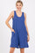 woman wearing a blue sleeveless romper with side pockets and a loose fit