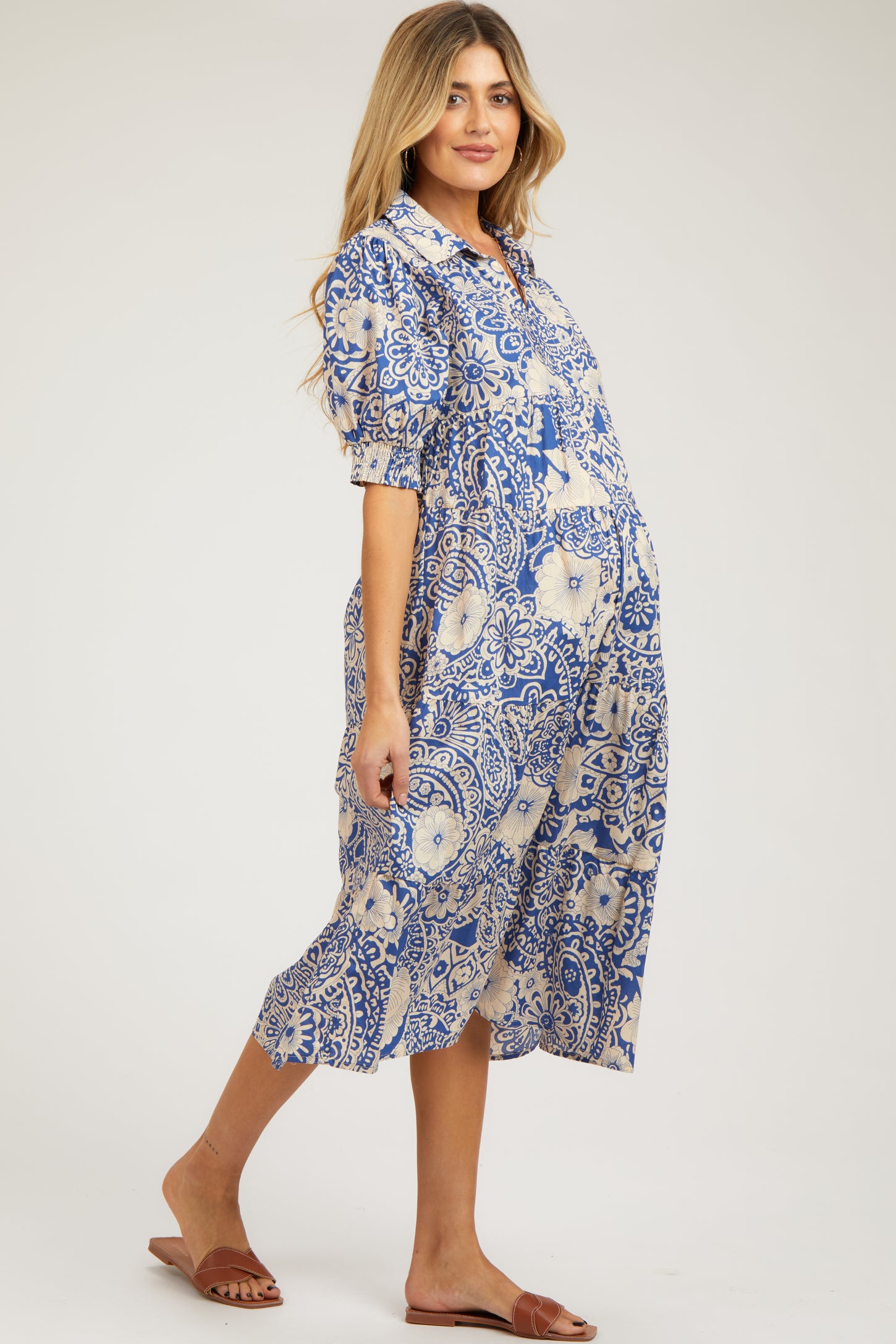 woman wearing a blue and white patterned maternity dress with puff sleeves and a flowing silhouette, showing her baby bump
